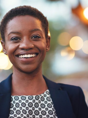 Portrait african american woman smiling confident female in city evening with lights in background